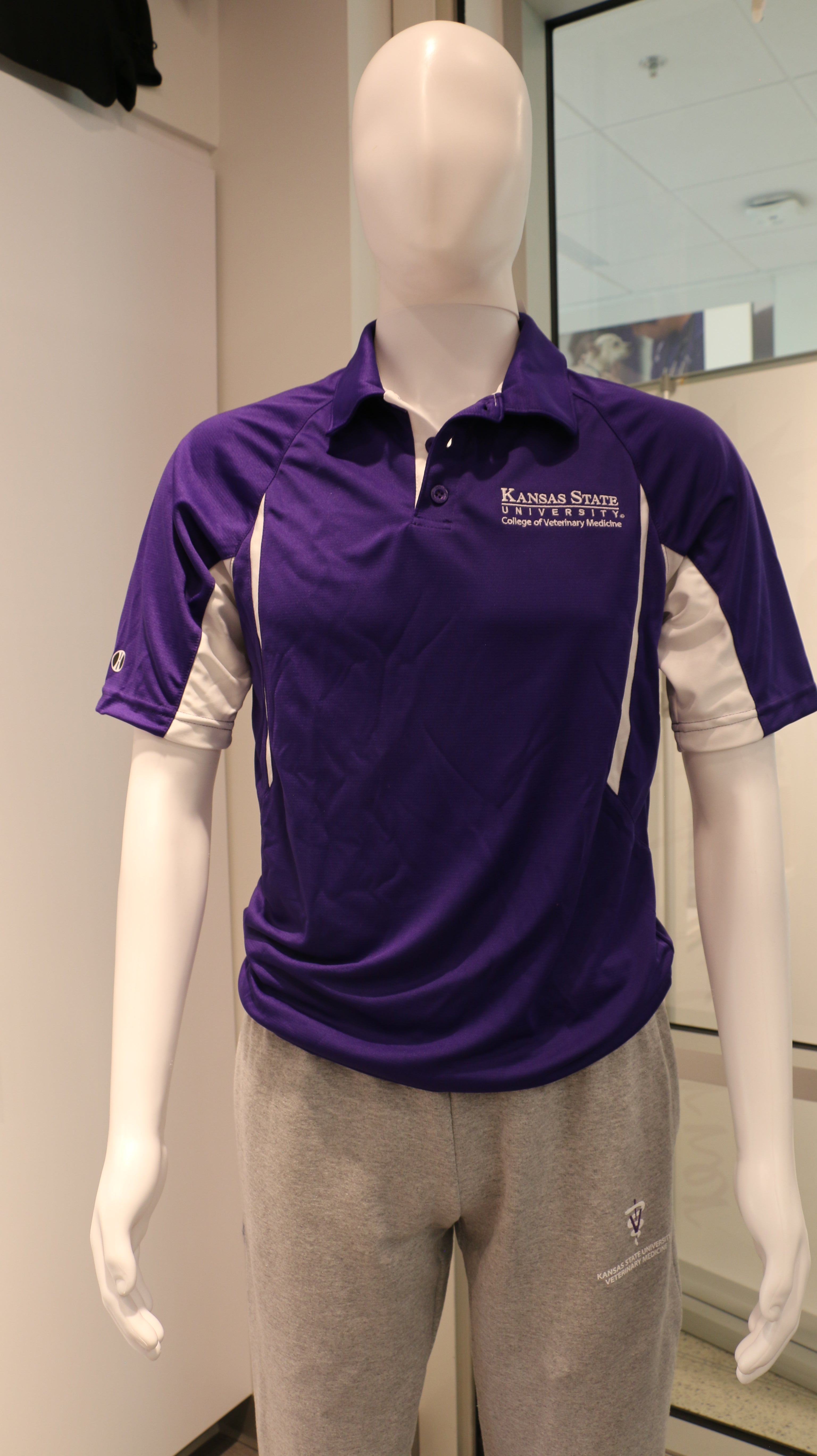 Men's Holloway Avenger Polo Shirt in purple, displayed on a mannequin with gray trousers.
