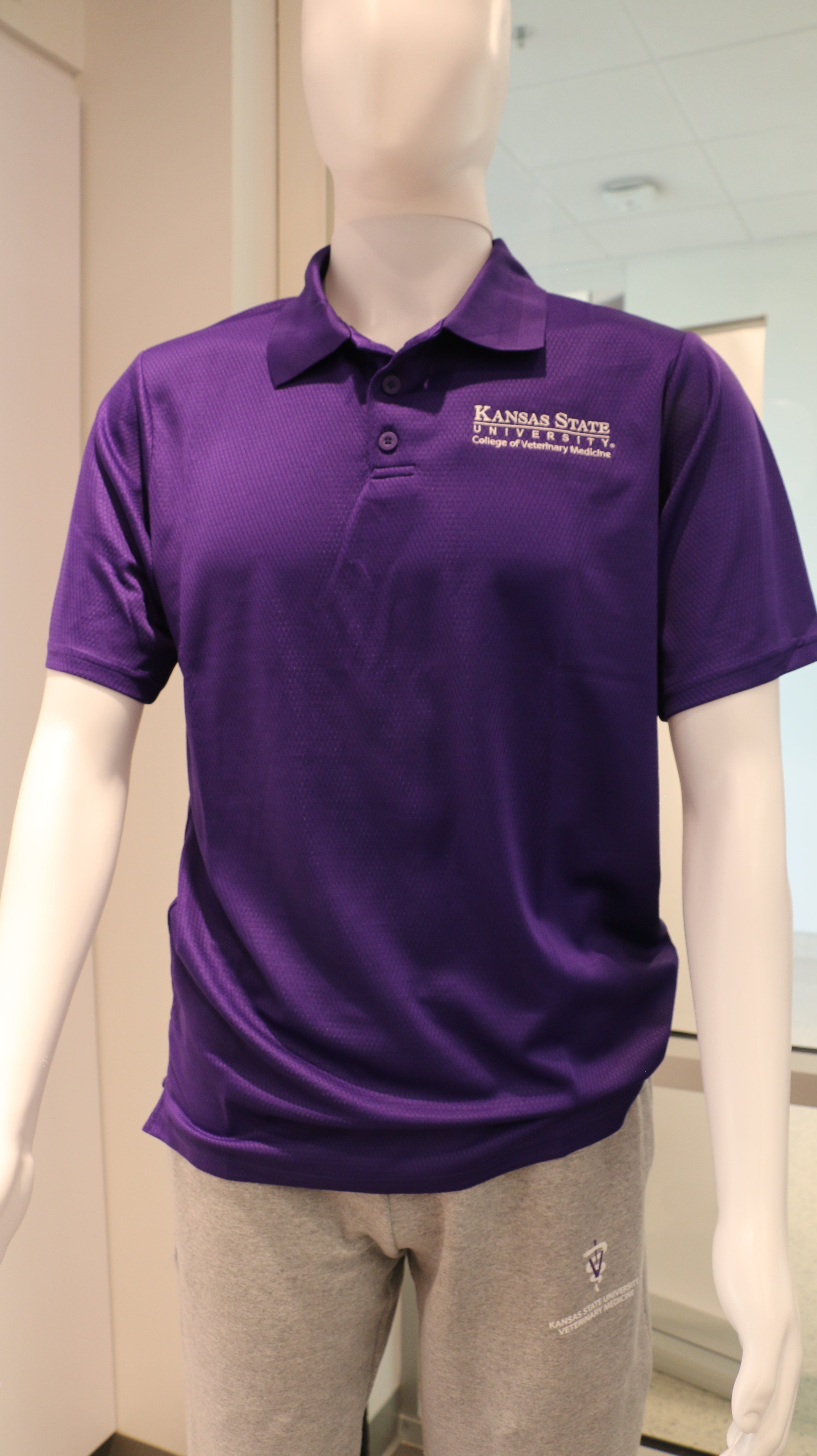 A purple polo shirt displayed on a mannequin, featuring short sleeves and a collar with a white CVM logo. 