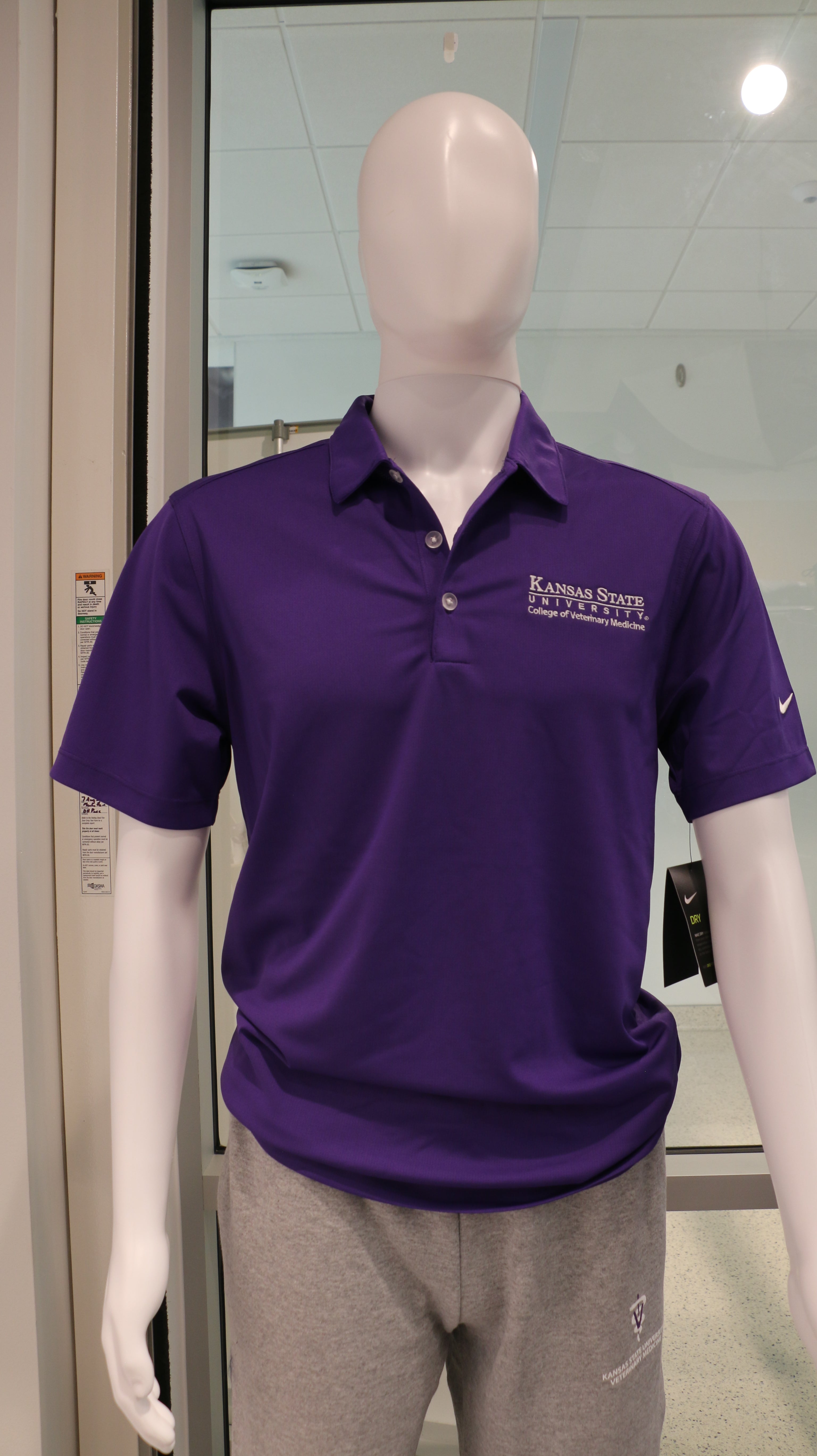 A mannequin wearing a purple Nike polo shirt with white CVM logo on the upper left side. 