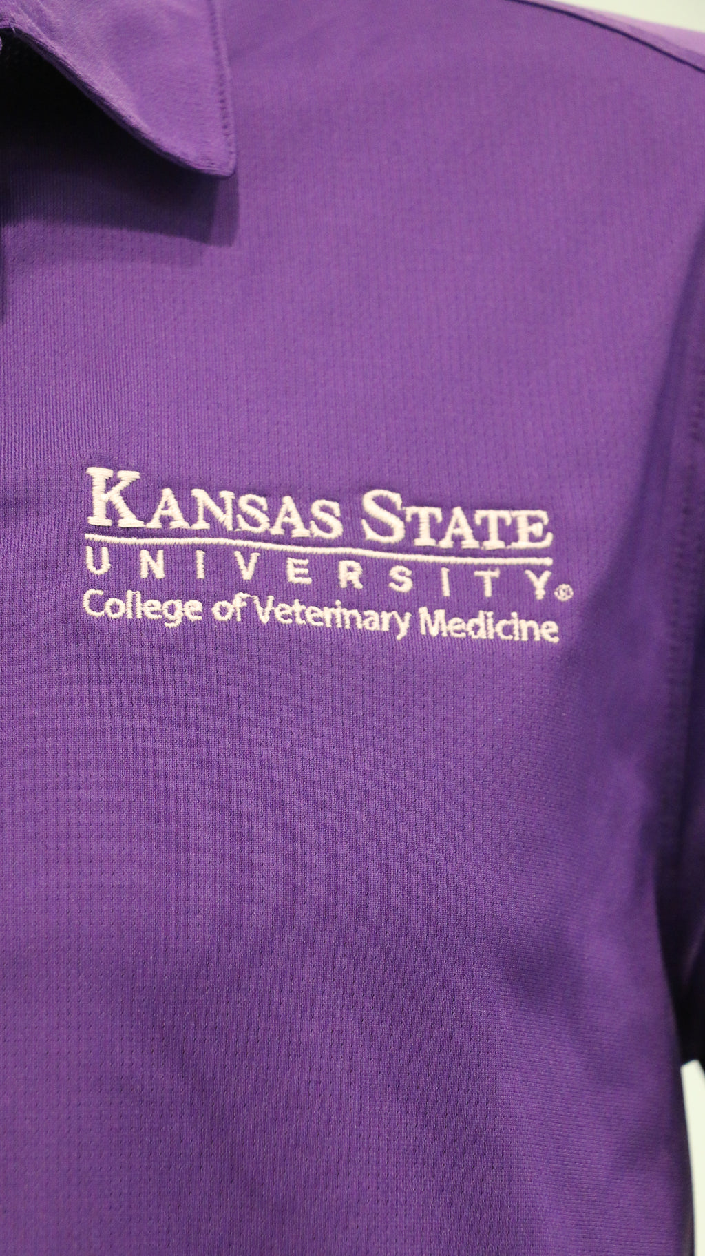 A close-up of the white CVM logo on the upper left side of the polo. 