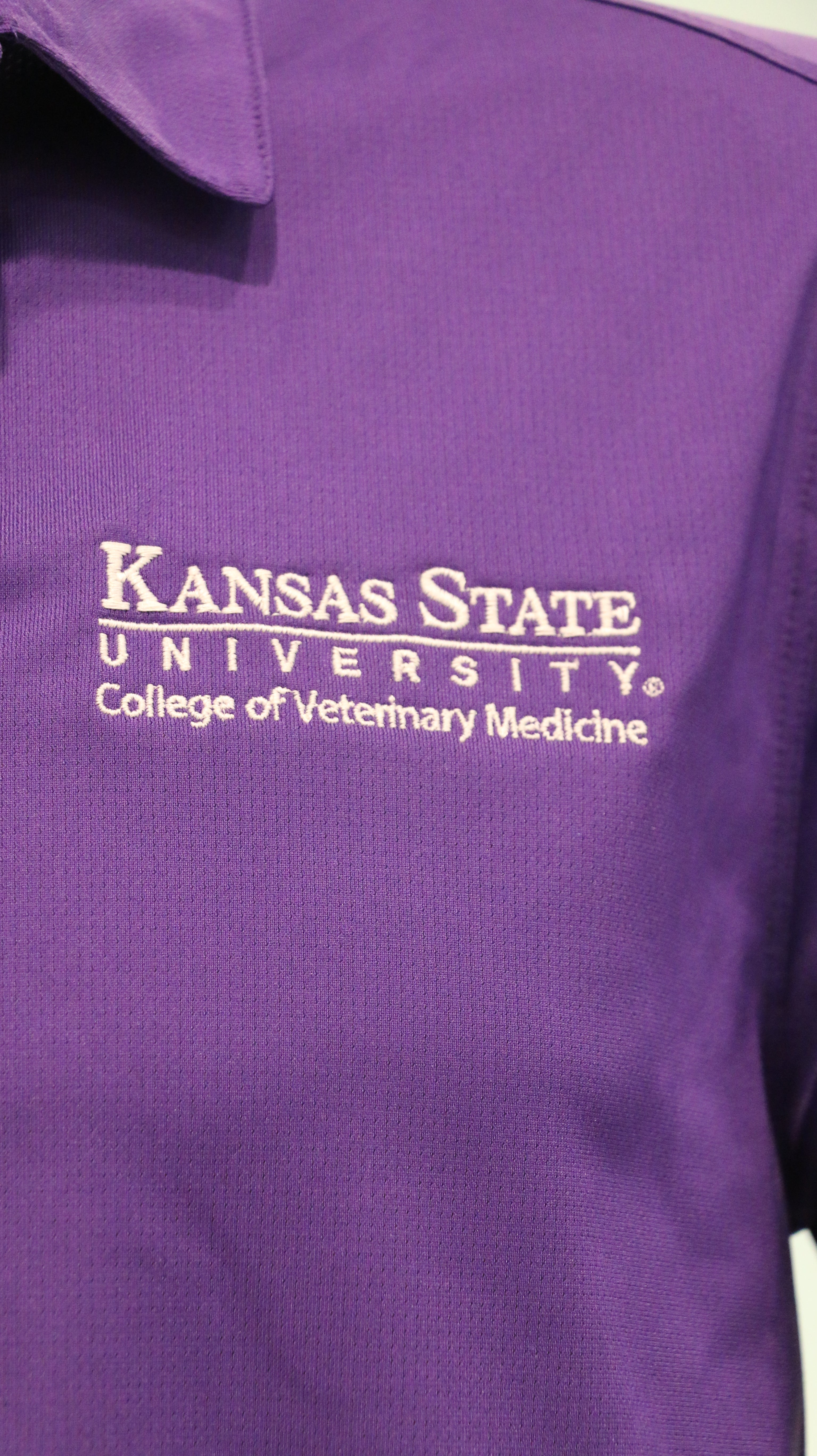 A close-up of the white CVM logo on the upper left side of the polo. 