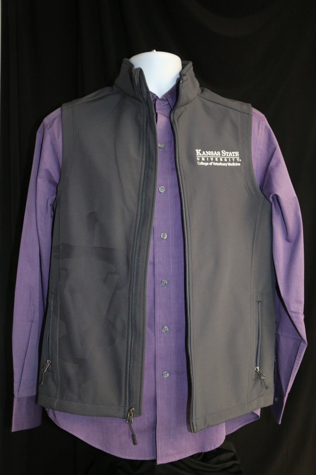 Men's gray soft-shell vest with laser etched Caduceus symbol, displayed over a purple shirt. The vest features zipper pockets and a white CVM logo on the upper left side. 
