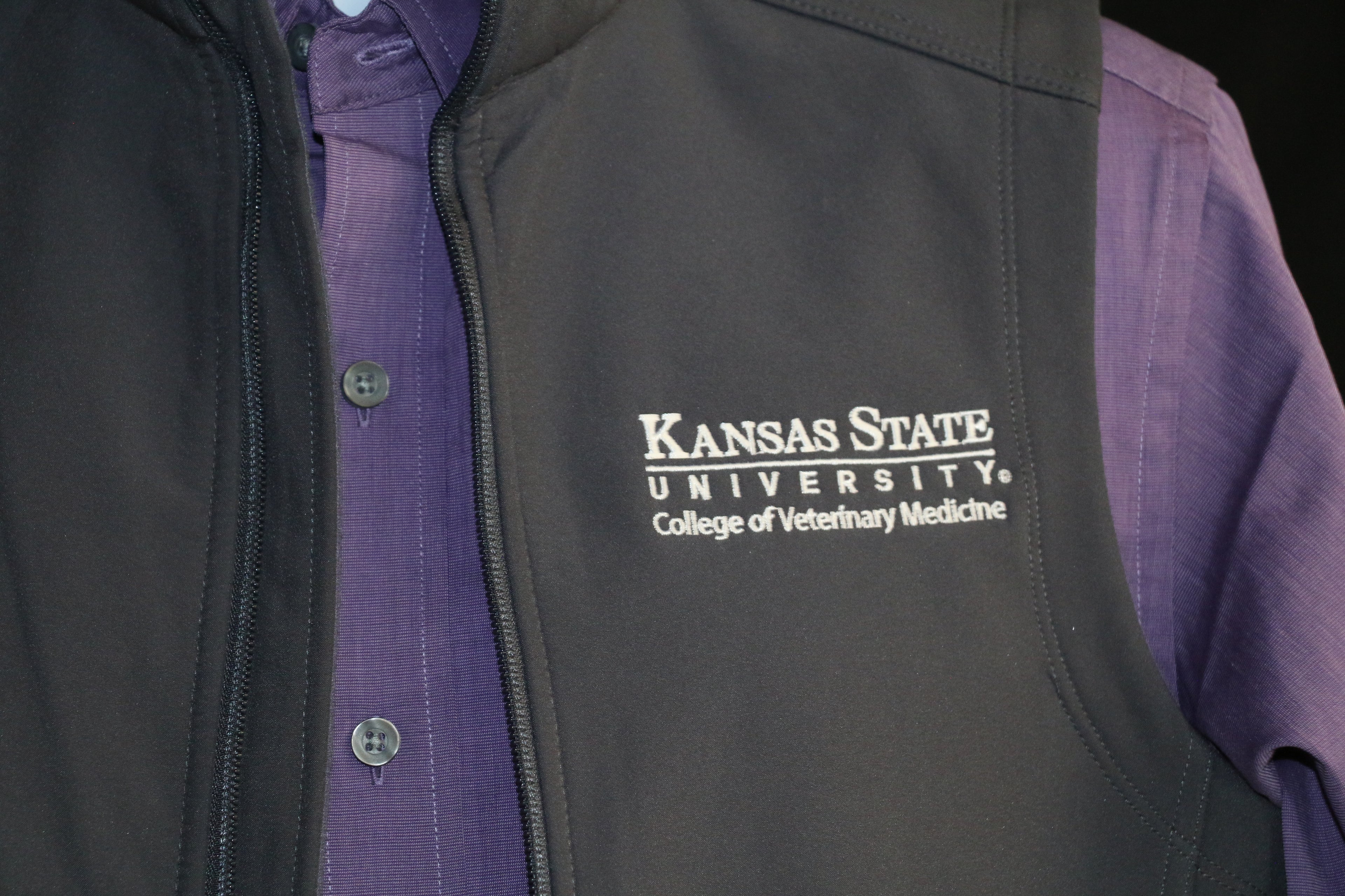 A close-up view of the white CVM logo on the upper left side of the vest. 