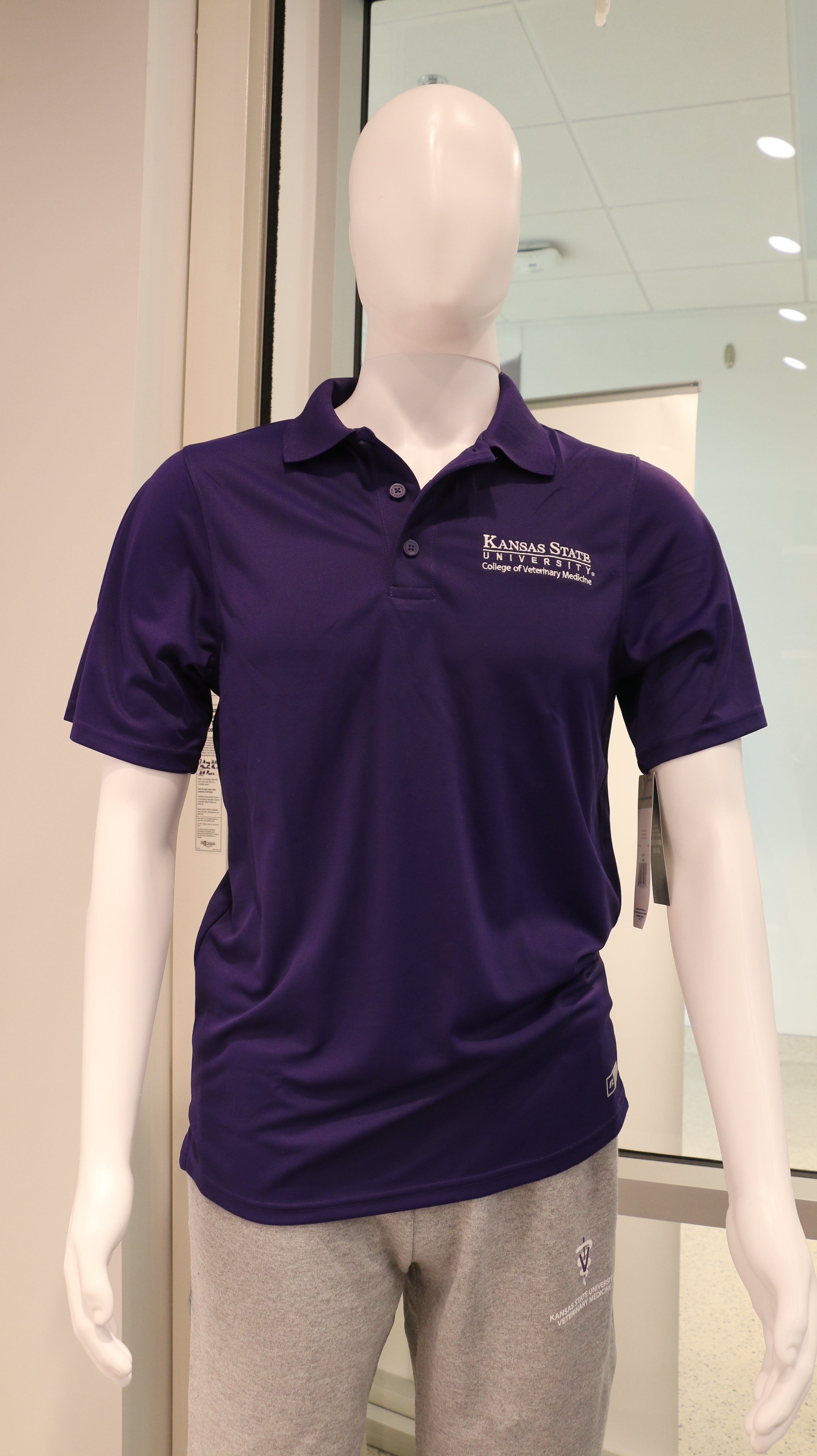 Men's Russell Athletic purple polo shirt with a white CVM logo on a mannequin. 