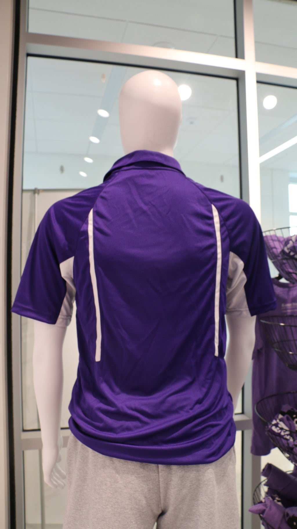 Rear view of the Men's Holloway Avenger Polo Shirt in purple, displayed on a mannequin with gray trousers.