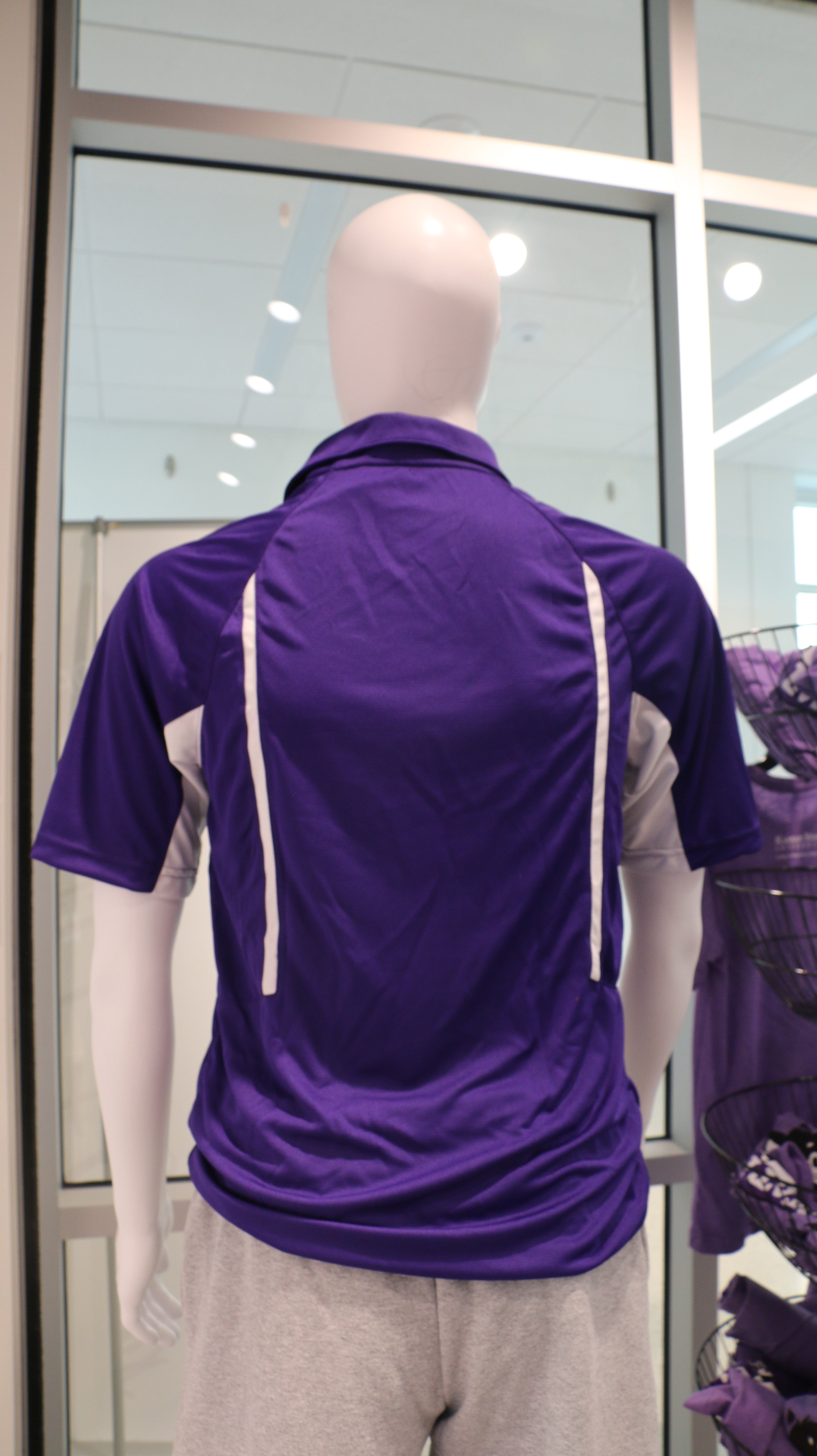 Rear view of the Men's Holloway Avenger Polo Shirt in purple, displayed on a mannequin with gray trousers.