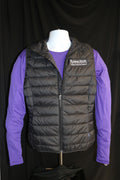 A mannequin wearing a black quilted puffer vest with zippered pockets, white K-State logo, and a stand-up collar, paired with a purple shirt.