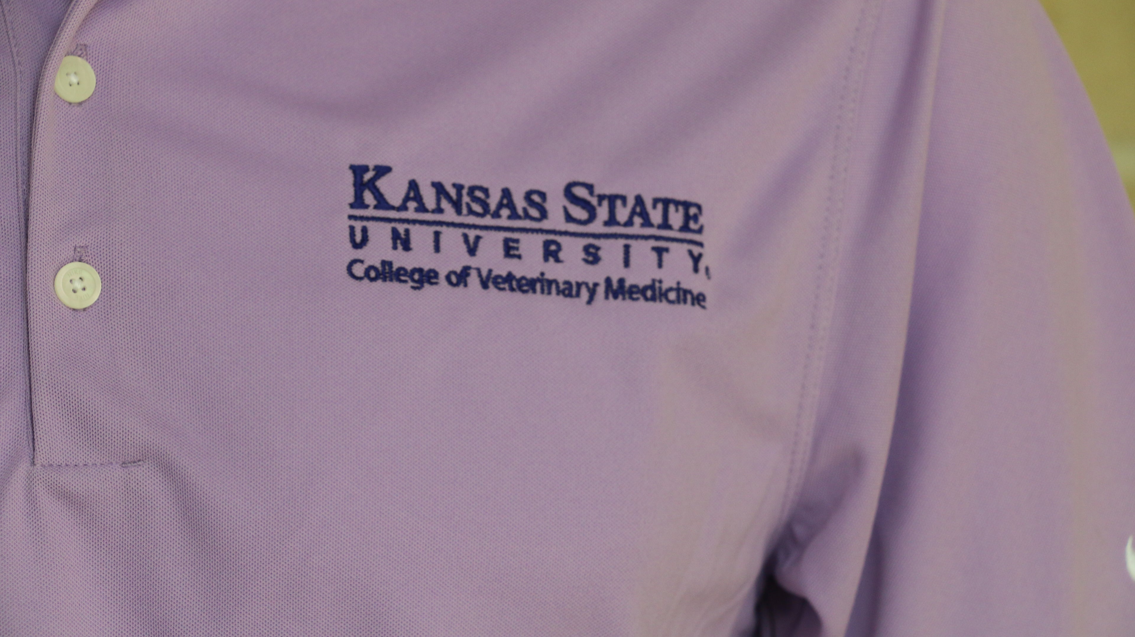A close-up view of the dark purple embroidered K-State CVM logo on the upper left chest area. 
