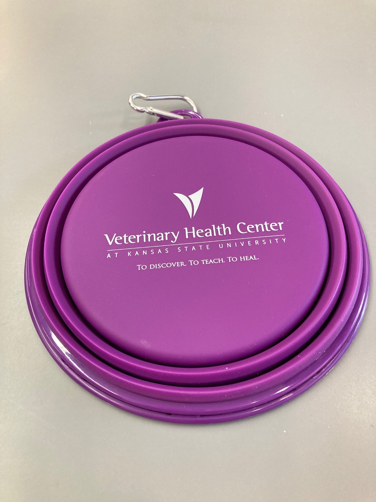 A 32oz purple collapsible silicone pet bowl displayed open and empty with a white Veterinary Health Center logo in the center. 