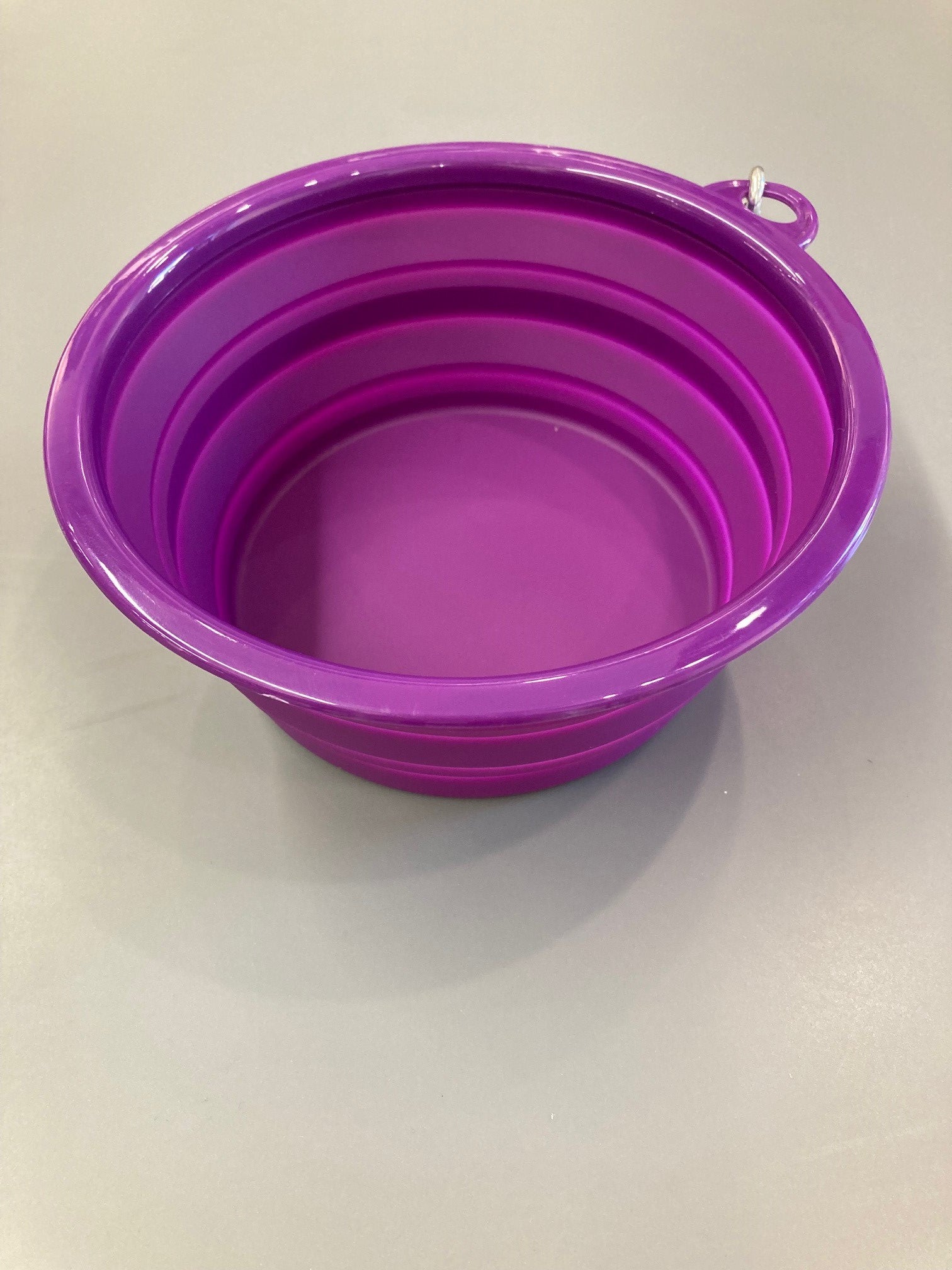 A 32oz purple collapsible silicone pet bowl displayed open and empty with a white Veterinary Health Center logo in the center. 