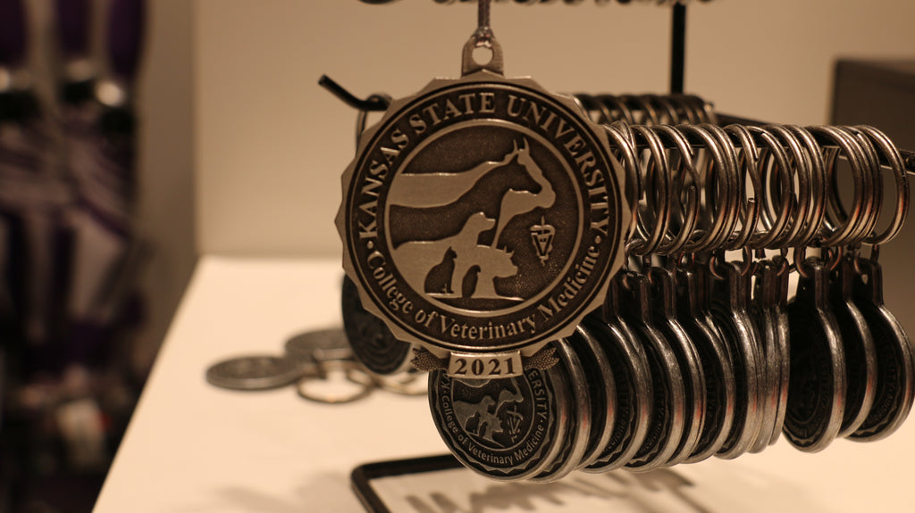 A pewter Christmas ornament with a university logo and the year 2021 inscribed on it, displayed on a chain.