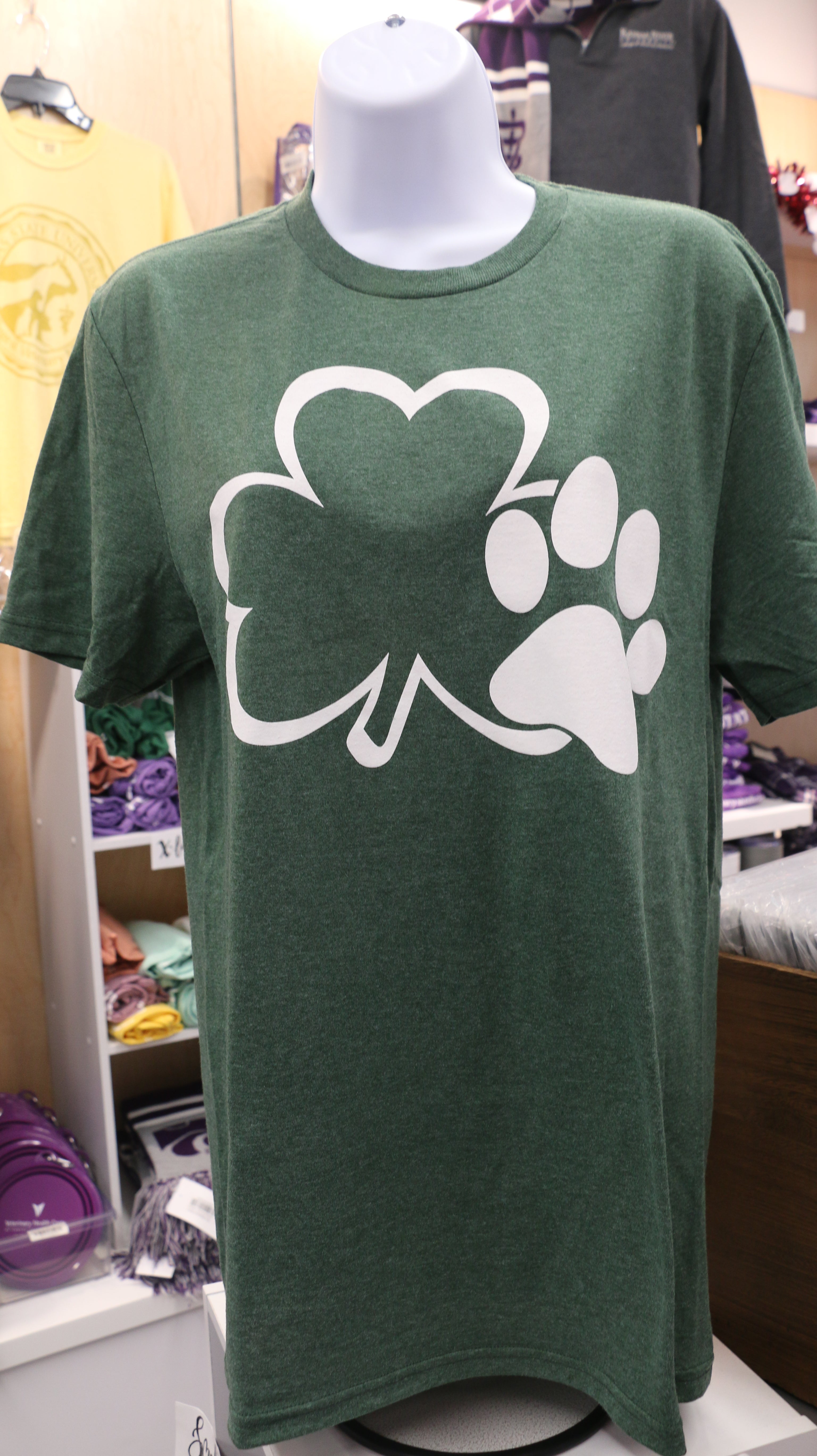 Green t-shirt with a white graphic design of a clover and a paw print on it, displayed on a mannequin.