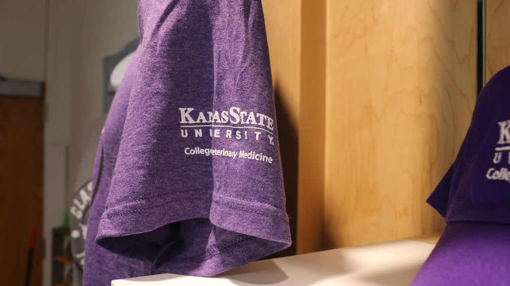 A close-up of the left sleeve where a white K-State CVM logo is printed. 