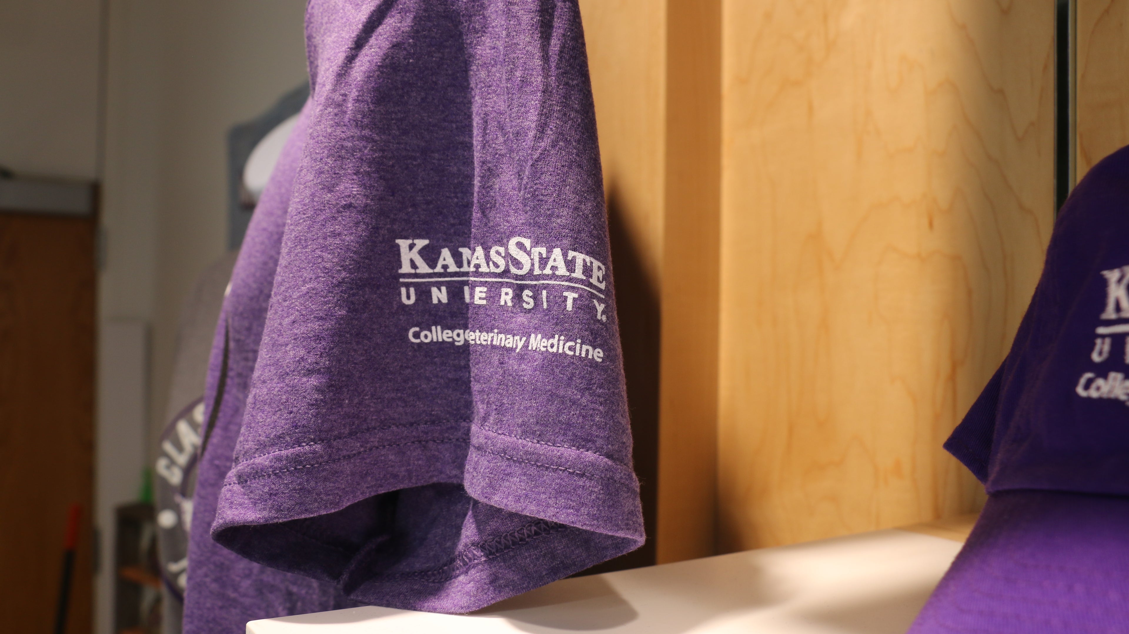 A close-up of the left sleeve where a white K-State CVM logo is printed. 
