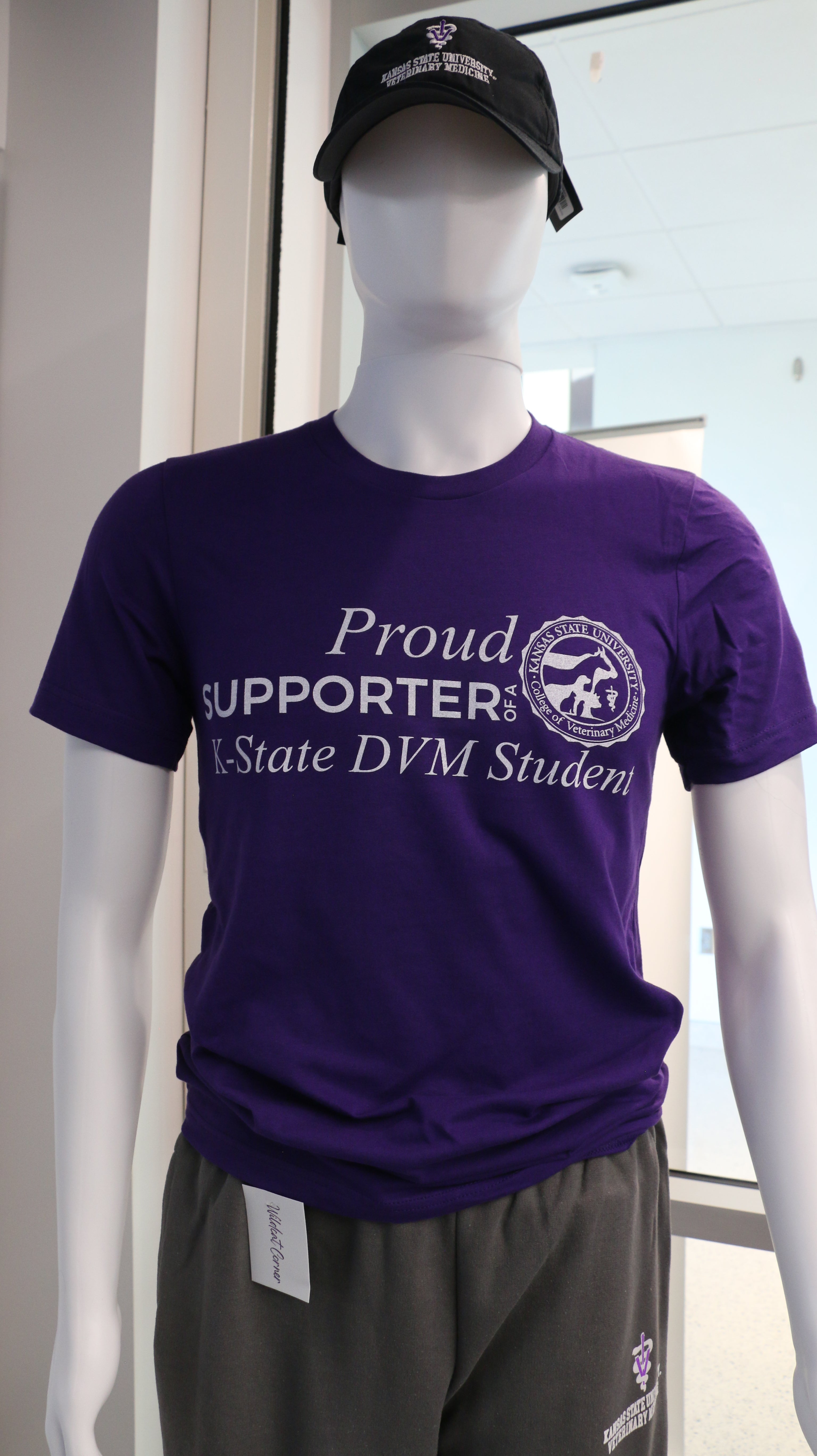 A purple Bella canvas T-shirt displayed on a mannequin, with the text 'PROUD SUPPORTER OF A K-STATE DVM STUDENT' printed on the front.