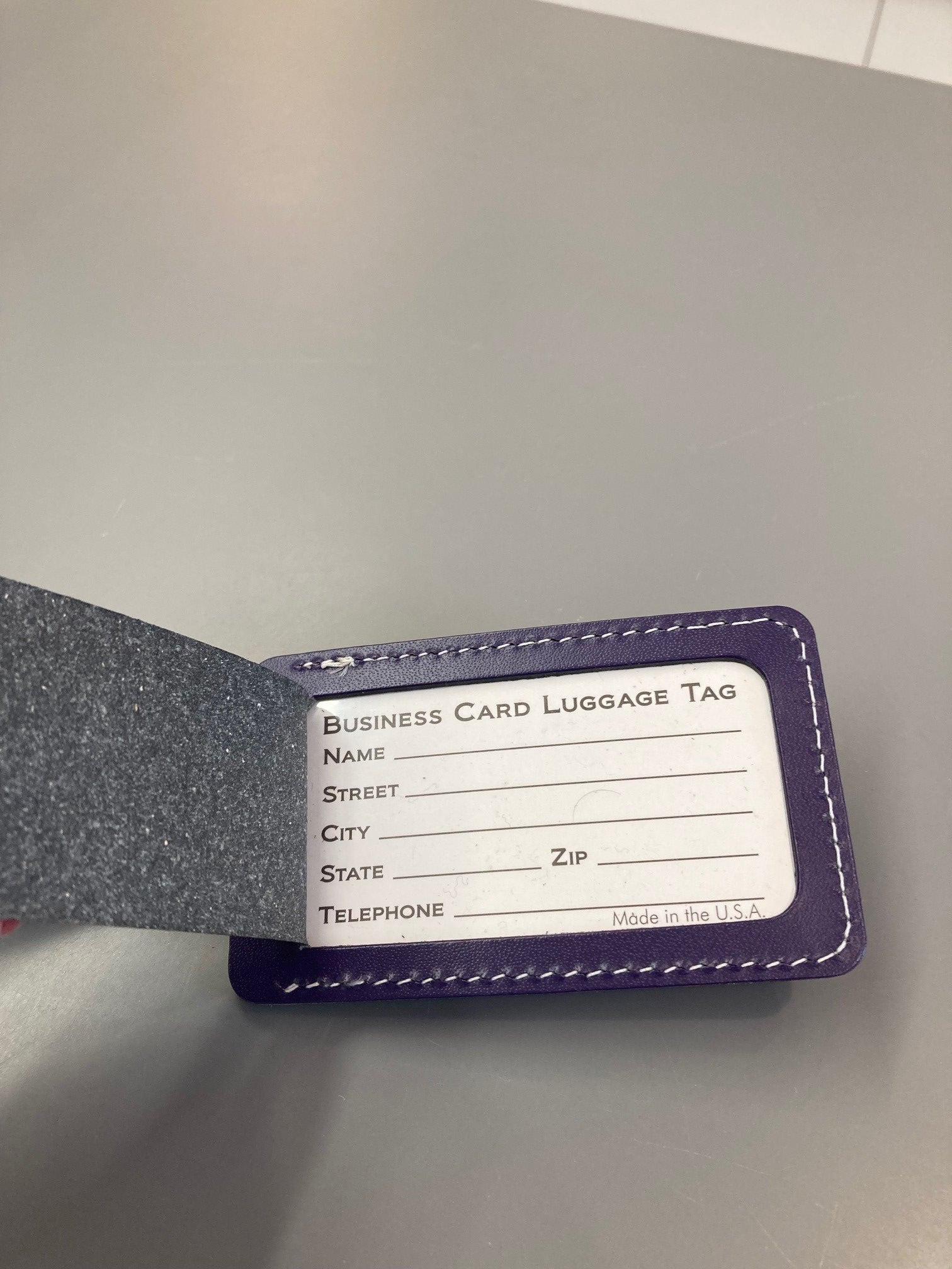 An inside view of the purple leather luggage tag where a luggage business card can be inserted for identification. 