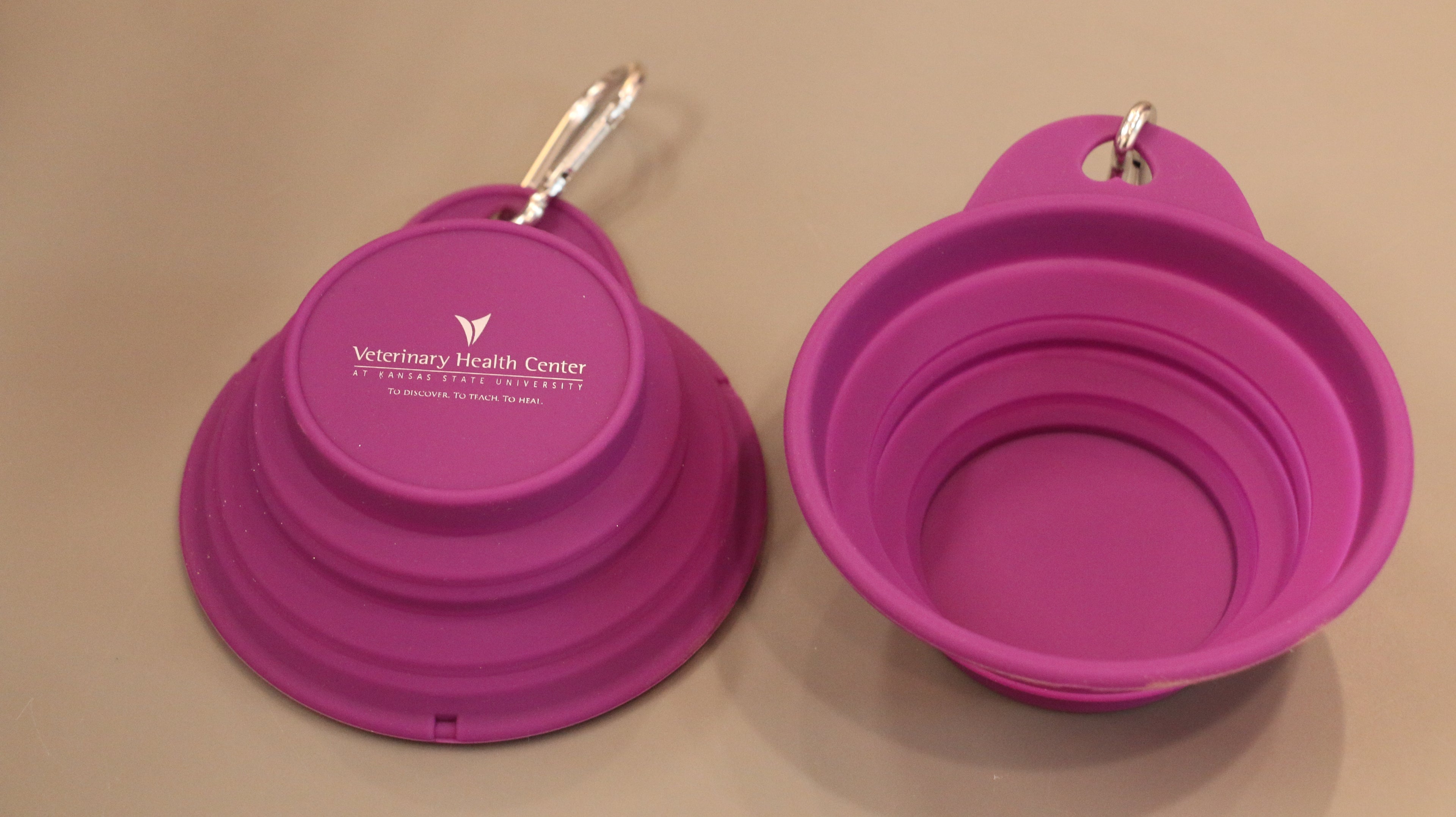 An 8oz purple collapsible silicone pet bowl with a clip, displayed from different angles with a "Veterinary Health Center" white logo in the center. 