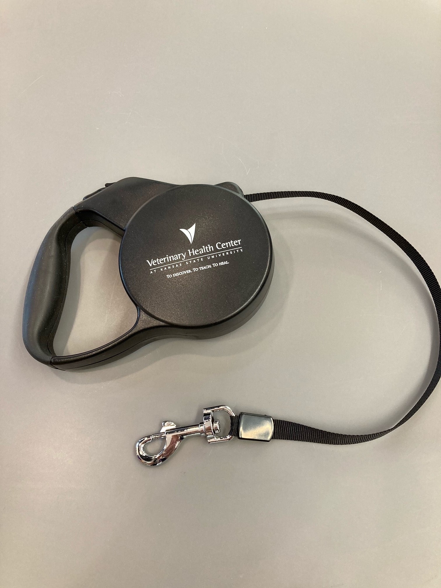 A black retractable pet leash with a white Veterinary Health Center logo. 