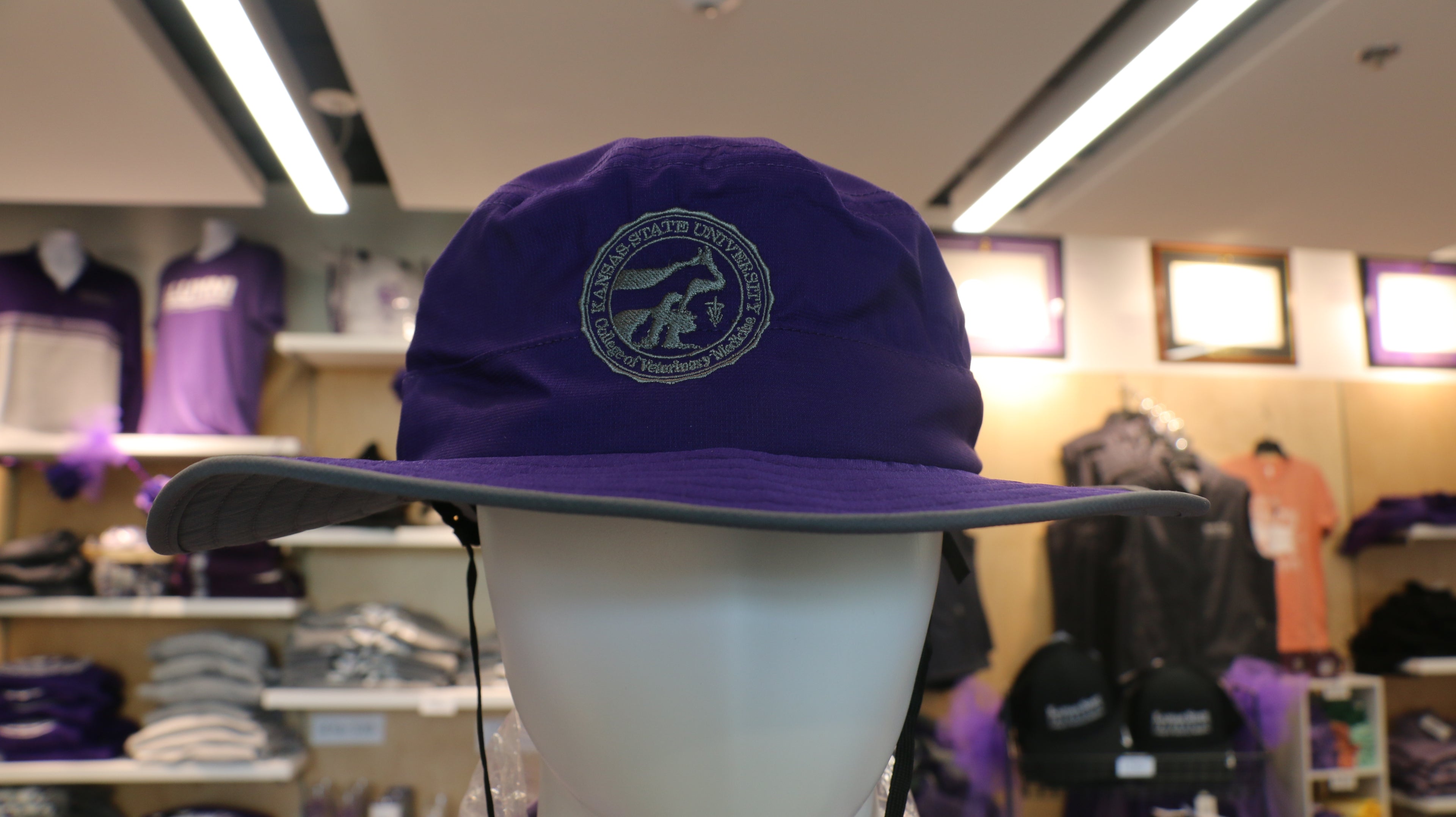 A purple wide brim sun hat on a mannequin with the CVM seal. 