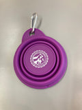 A purple collapsible silicone pet bowl with a clip for attaching to a leash or belt buckle.