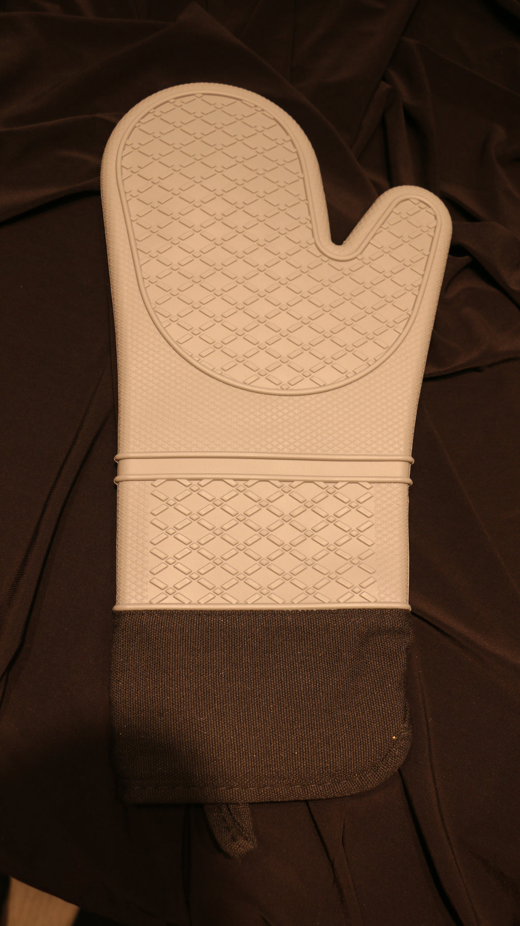 A rear view of a silicone oven mitt with a light grey base color and black fabric cuff.