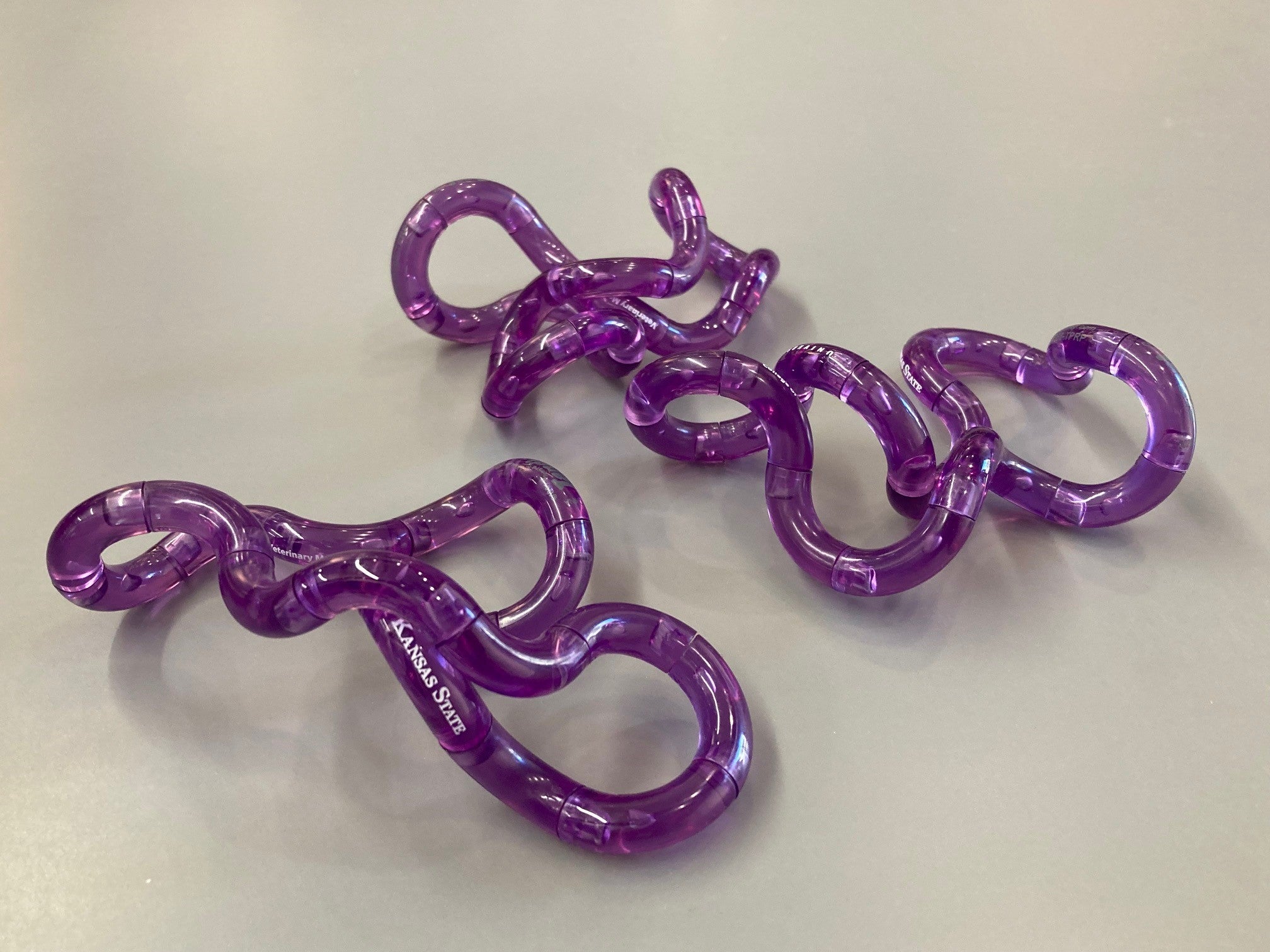 A purple fidget toy with a geometric design, consisting of movable intertwined loops. 