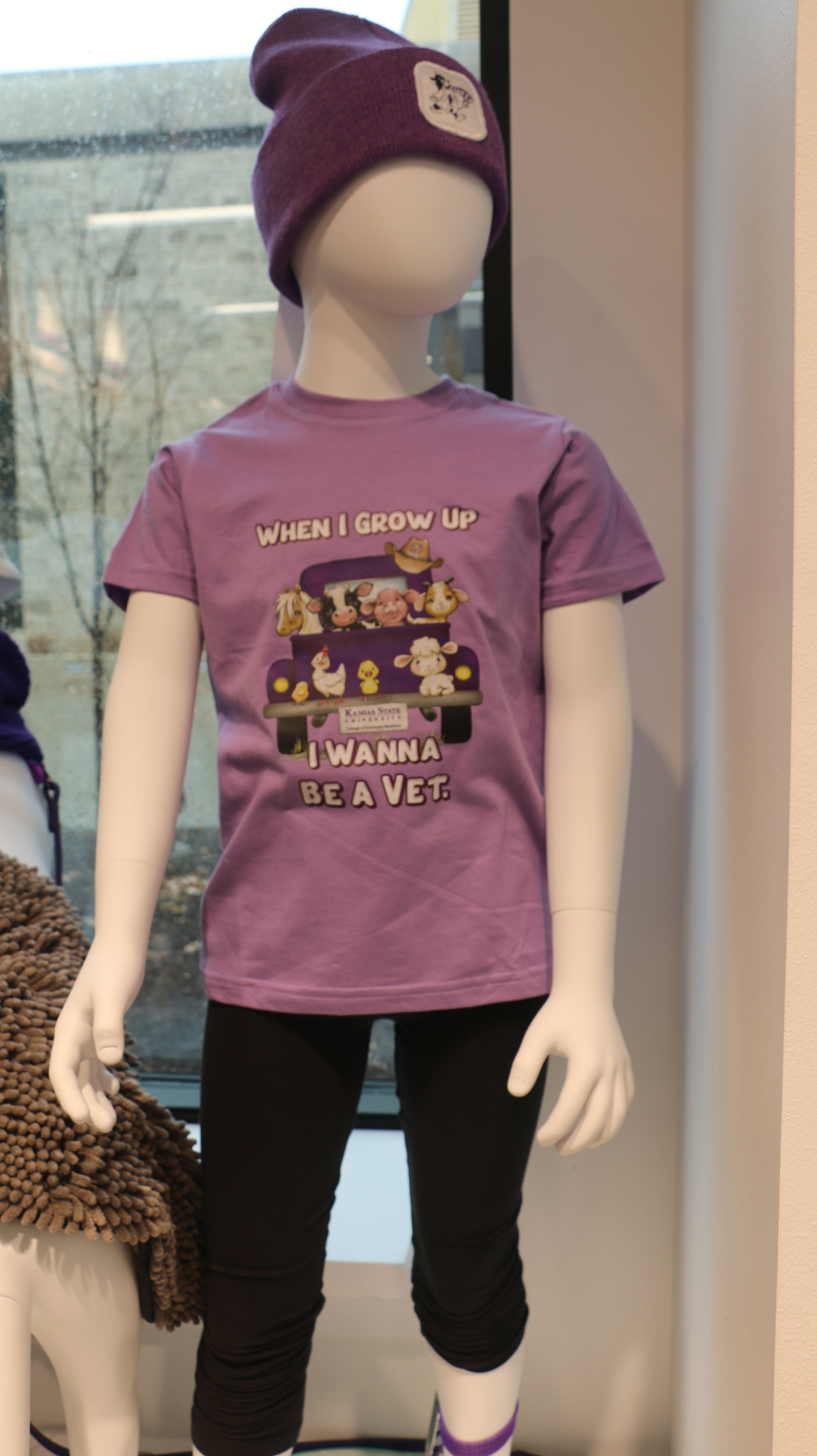 A lavender-colored short sleeve youth t-shirt with an illustration of different animals in the back of a truck and the text 'When I grow up I want to be a Vet'.