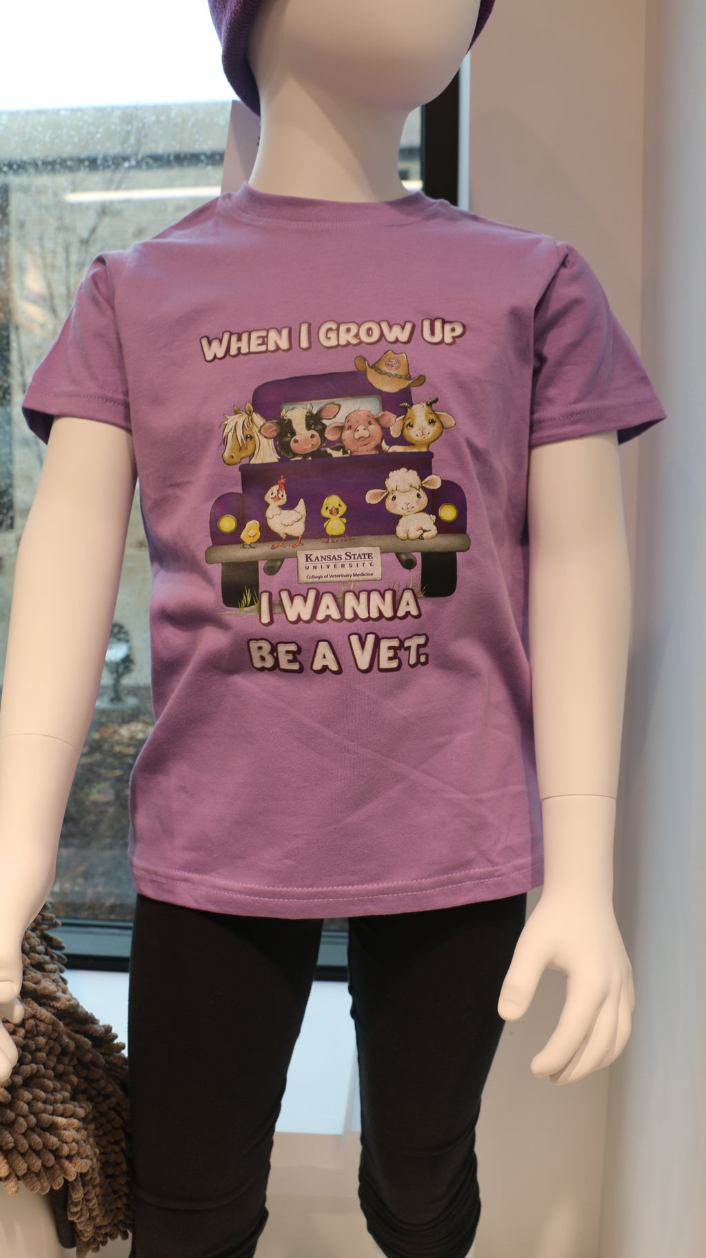 A lavender-colored short sleeve youth t-shirt with an illustration of different animals in the back of a truck and the text 'When I grow up I want to be a Vet'.