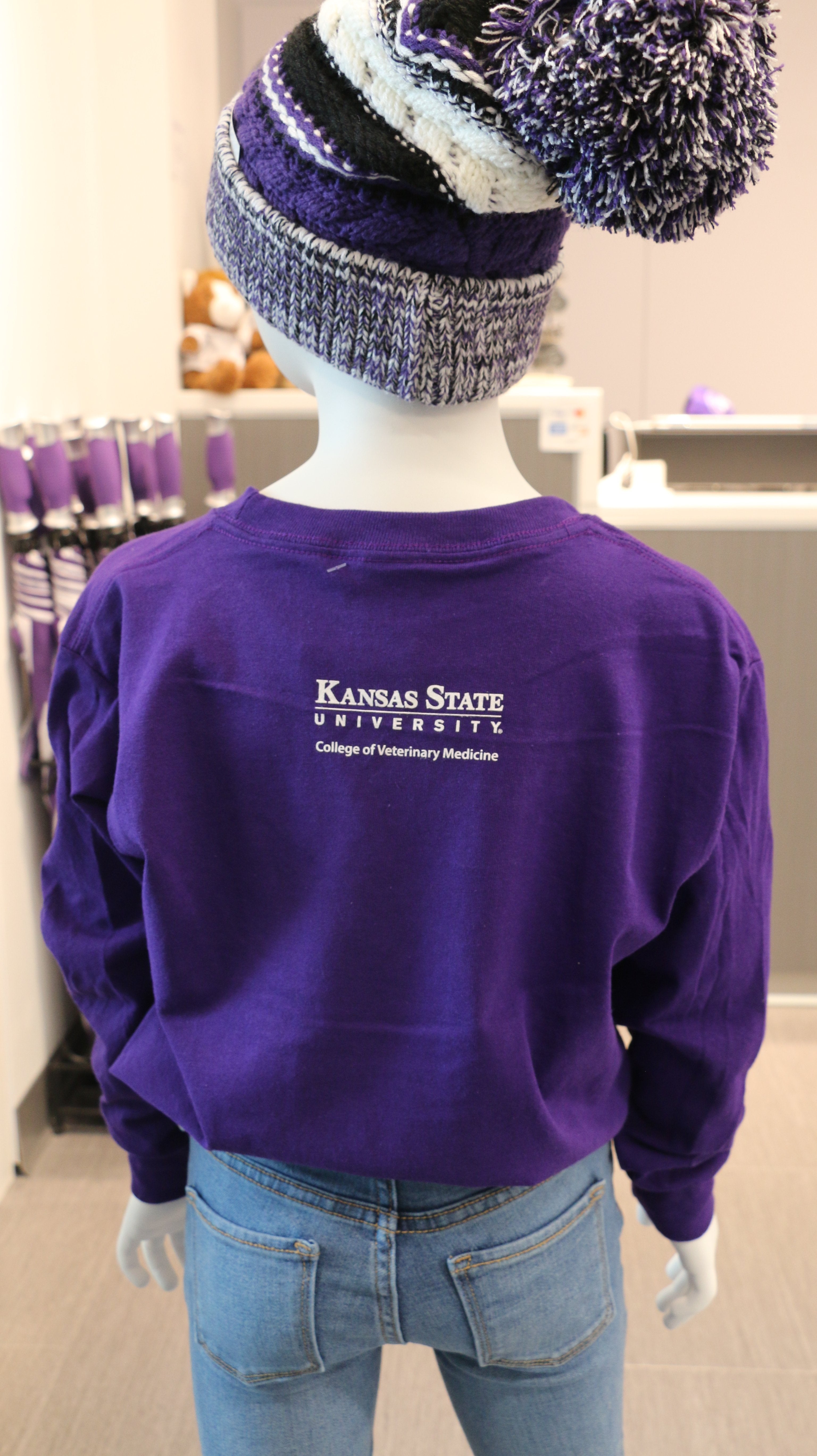 A rear view of the youth Gildan long sleeve purple t-shirt with a white CVM logo in the upper middle back area. 